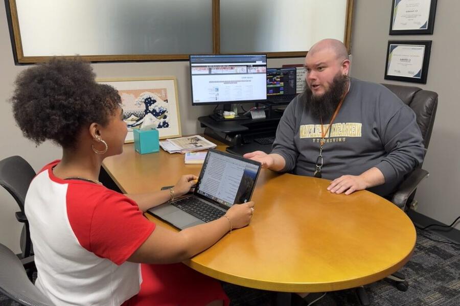 The NWU advising director in his office helping a student with her schedule.